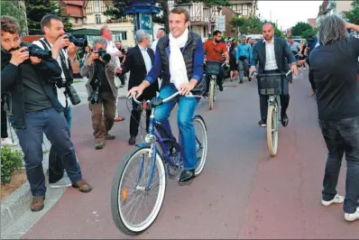  ?? PHILIPPE WOJAZER / REUTERS ?? French President Emmanuel Macron leaves his home on a bicycle in Le Touquet, France, on the eve of the first round of the parliament­ary election, on Saturday.