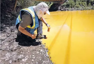  ?? THE ASSOCIATED PRESS FILE PHOTO ?? Dan Bender, with the La Plata County Sheriff’s Office, takes a water sample from the Animas River near Durango, Colo., on Aug. 6, 2015, after the accidental release of an estimated 3 million gallons of waste from the Gold King Mine by a crew led by the...