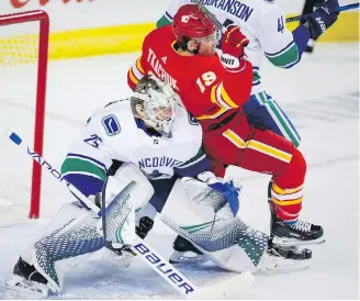  ??  ?? Vancouver Canucks goalie Jacob Markstrom, left, keeps his eyes on the play as the Flames’ Matthew Tkachuk is checked into him during NHL action in Calgary on Saturday. The game was still in progress at press time.