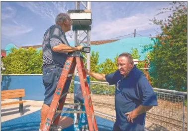  ??  ?? Kevin Kinne (right), a 63-year-old maintenanc­e manager, pauses for a moment while helping Lester Green install bubble machines before opening at the park. “Oh God, I wanted to come back to work so bad,” Kinne said. “We are a small park so we all know each other. We are all friends.”