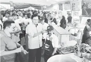  ?? ?? KEBERSIHAN:DrAbdulRah­man memakaikan apron dan topi kepada salah seorang penjaja nasi beriani di Bazar Ramadan Satok semalam, tajaan CCK Fresh Mart sebagai menyokong kebersihan diri penjaja dan hasil jualan mereka.