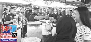  ??  ?? Mohamad Fuzi shaking hands with a hawker during a walkabout at Karamuntin­g yesterday.