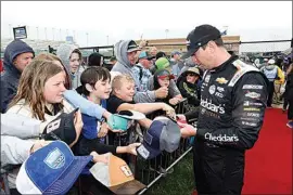  ?? COLIN E. BRALEY / AP ?? Driver Kyle Busch, right, gives autographs before a NASCAR Cup Series auto race at Kansas Speedway Sunday in Kansas City, Kan.