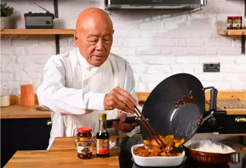  ?? ?? Ken Hom finishes off a dish in a wok Ken Hom; Lee Kum Kee