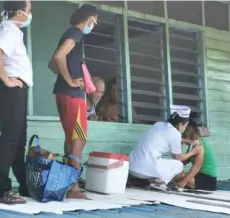  ??  ?? A nurse administer­s the vaccine to residents on the roof of the longhouse verandah on the upper floor.