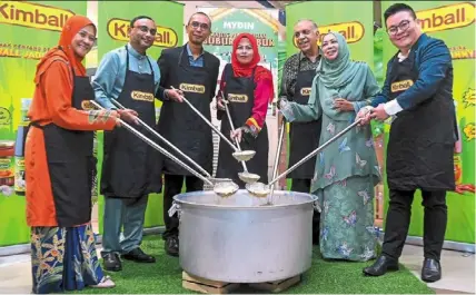  ?? Photos: Bernama ?? noraini (fourth from left) and ameer ali (third from right) stir bubur lambuk before distributi­ng the porridge at the ‘happening raya’ campaign launch. —