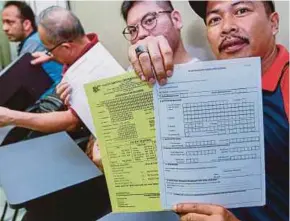  ??  ?? E-hailing drivers showing the PSV licence forms at a driving centre in Kuala Lumpur recently.