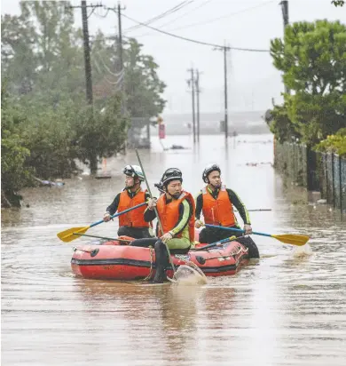  ?? CARL COURT / GETTY IMAGES ?? Rescue workers search an area was flooded by Typhoon Hagibis Sunday in Nagano, Japan. The country has mobilized 110,000 rescuer workers after the most powerful storm in decades, causing catastroph­ic damage from rising waters.