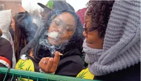  ?? TREVOR HUGHES/USA TODAY ?? Kennya Anderson of Chicago passes a joint to her friend as marijuana smoke fills the air during the Denver 420 rally.