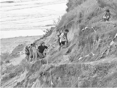  ??  ?? Some visitors risk danger by scaling the steep cliff that leads to the beach, after the footpath was hit and destroyed by strong waves.