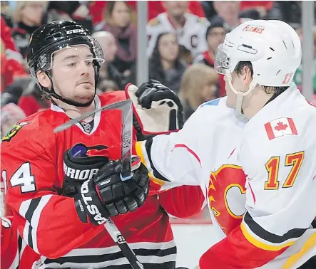  ??  ?? Tim Erixon of the Blackhawks mixes it up with Lance Bouma of the Flames during NHL action on Sunday at the United Center in Chicago. The Flames were high on Erixson as a prospect but were forced to deal him to the Rangers for a pair of draft picks.