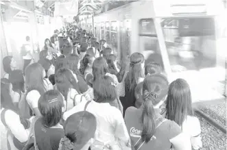  ??  ?? Passengers wait for a train coach at the Edsa station of the Light Rail Transit 1. The railway set a record on Monday when it carried 620,987 passengers.