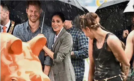  ?? — AFP ?? Weathering it out: Harry and Meghan watching an aboriginal dance show at Victoria Park in Dubbo.