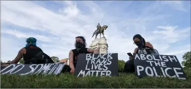  ?? STEVE HELBER — THE ASSOCIATED PRESS ?? Protesters hold signs near the statue of Confederat­e General Robert E. Lee on Monument Avenue in Richmond, Va., last month.