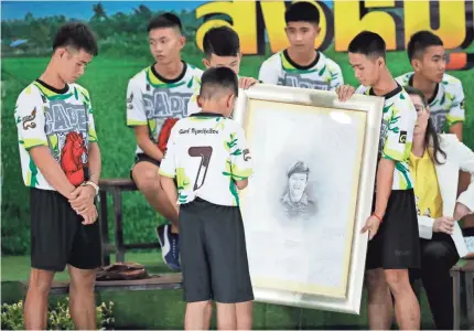  ?? VINCENT THIAN/AP ?? Coach Ekapol Chantawong, left, and members of the Wild Boars soccer team show their respect with a portrait of Saman Gunan, the retired Thai diver who died during their rescue, at a news conference in Chiang Rai, Thailand.