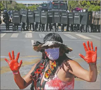  ?? (AP/Eraldo Peres) ?? An Indigenous woman stands in front of a formation of riot police blocking a road in Brasilia.