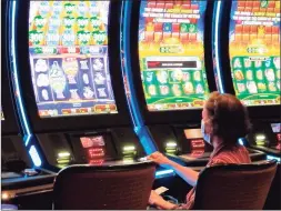  ?? Wayne Parry / Associated Press ?? A woman plays a slot machine at the Golden Nugget casino in Atlantic City, N.J. on July 2. A report released Monday by the national trade associatio­n for the U.S. casino industry found that America’s casinos won 81% of the amount of money during the third quarter of this year that they did in the third quarter of 2019, when there was no virus pandemic.