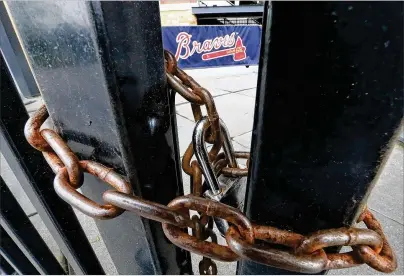  ?? CURTIS COMPTON/AJC 2020 ?? The third base gate at Truist Park is chained shut March 31, 2020. A year after the worldwide coronaviru­s pandemic stopped all the games in their tracks, the aftershock­s are still being felt across every sector.