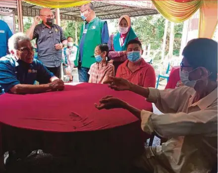  ?? BERNAMA PIC ?? Minister in the Prime Minister’s Department (Special Functions) Datuk Seri Mohd Redzuan Md Yusof (seated, left) engaging with residents during the Jelajah Pak Wan Prihatin Tour programme at Kampung Pantai Belimbing in Alor Gajah, yesterday.