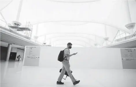  ?? DAVID ZALUBOWSKI/AP ?? A traveler passes an area under constructi­on July 2 on the way to the gates at Denver Internatio­nal Airport.