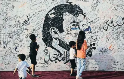  ?? NASEEM ZEITOON / REUTERS ?? Unos niños pasan por delante de un retrato del emir Tamim bin Hamad al Zani pintado en Doha