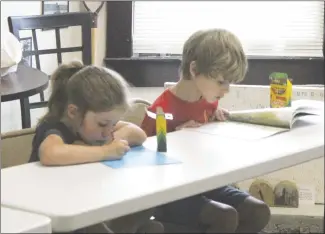  ?? Brodie Johnson • Times-Herald ?? Lillian and Liam Hennessey work on their tall tale during the St. Francis County Museum’s program on Thursday. The museum is hosting programs for children each Thursday this month.