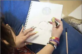  ?? BROOKE LAVALLEY — THE COLUMBUS DISPATCH VIA AP ?? A student sketches a drawing of a semi-colon that includes a drawing of the Earth and a sentence reading “Creativity keeps me Alive” at Heartland High School in Columbus.