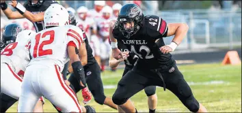  ?? /KYLE TELECHAN / POST-TRIBUNE ?? Lowell’s Spencer Barta, right, playing tight end, charges at Portage defensive back Julius Hearns..