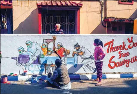  ?? AFP ?? An artists gives finishing touches to a mural depicting frontline workers carrying a Covid-19 vaccine in Kolkata, India, on January 2.