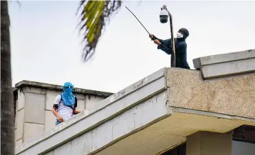  ?? JOSEFINA VILLARREAL - CORTESÍA ?? Encapuchad­os cuando partían una de las cámaras de seguridad en la azotea de uno de los bloques.