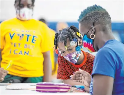  ?? Benjamin Hager Las Vegas Review-journal @benjaminhp­hoto ?? Kanita Carter, right, explains the voter registrati­on process to Kimberly Moore, 7, during a National Voter Registrati­on Day voter drive Tuesday at Democracy Preparator­y Academy at Agassi Campus in Las Vegas.