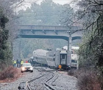  ?? BOB LEVERONE GETTY IMAGES ?? Investigat­ors make their way around the train wreckage under the Charleston Highway overpass where two trains collided early Sunday morning on February 4, 2018 in Cayce, South Carolina.