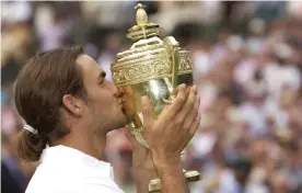  ?? Photograph: Tom Jenkins/The Guardian ?? Roger Federer kisses the Wimbledon trophy after winning his first singles final against Australia’s Mark Philippous­sis in 2003.