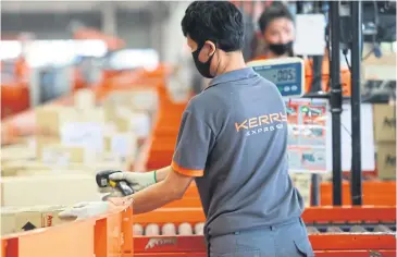  ?? SOMCHAI POOMLARD ?? An operations worker scans a parcel at a Kerry Express distributi­on centre in Samut Prakan province. The labour-intensive logistics and parcel delivery sector has been hampered by the pandemic.