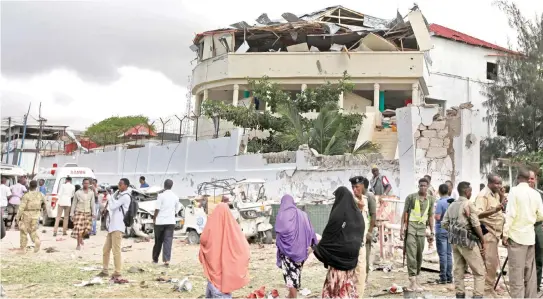  ??  ?? Somalis gather outside a destroyed building near a restaurant that was the scene of a car bomb blast and gunbattle in Mogadishu, Somalia on Thursday. (AP)