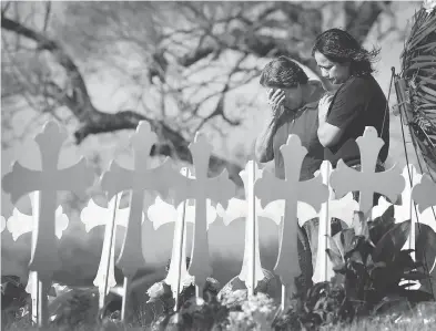  ?? SCOTT OLSON / GETTY IMAGES ?? Maria Durand, left, and her daughter Lupita Alcoces visit a memorial Tuesday where 26 crosses stand to honour the 26 victims killed in a mass shooting at the First Baptist Church of Sutherland Springs, Texas. Durand, who helps to teach Bible study at...