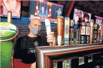  ?? DARREN MAKOWICHUK/POSTMEDIA ?? General manager Jason Reeb of The Cat ‘n Fiddle Pub pours a beer as Premier Jason Kenney announces new restrictio­ns in Calgary on Tuesday.