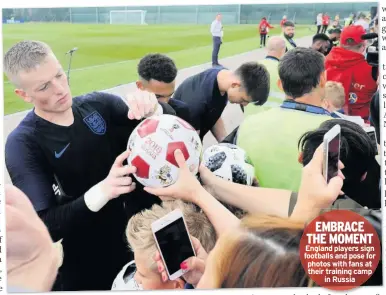  ??  ?? EMBRACE THE MOMENT England players sign footballs and pose for photos with fans at their training camp in Russia