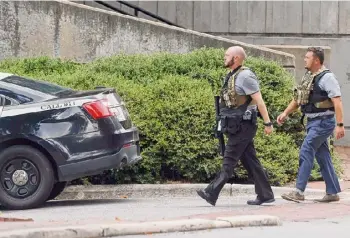  ?? Kaitlin Mckeown/associated Press ?? Two police officers move around a building on the University of North Carolina at Chapel Hill campus in Chapel Hill, N.C., on Monday after a report of an “armed and dangerous person” on campus.