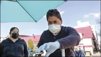  ?? ASSOCIATED PRESS ?? Ruth Palacios and Arturo Xelo, a married couple from Mexico, work at their fruit stand in the Corona neighborho­od of the Queens borough of New York on Tuesday.