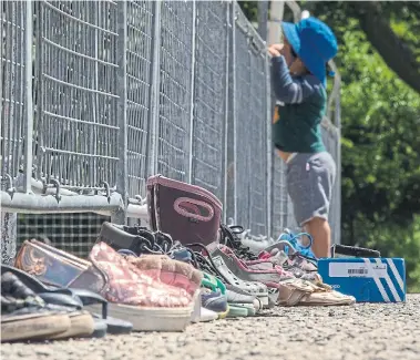  ?? RICK MADONIK TORONTO STAR ?? A child peers over a fence on Sunday at Queen’s Park, where a small memorial honours the 215 children whose remains were found in a mass grave at a former residentia­l school in Kamloops, B.C..