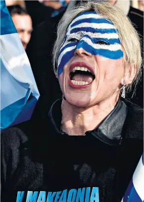  ??  ?? A woman, her face painted with the Greek flag, chants slogans during the demonstrat­ion in central Athens