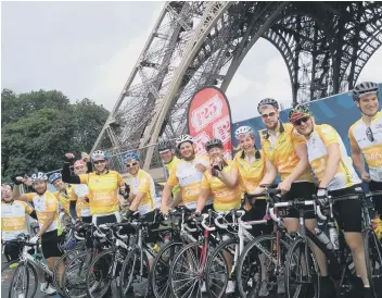  ??  ?? Thomas Cook cyclists celebrate the completion of their challenge at the foot of the Eiffel Tower in Paris.