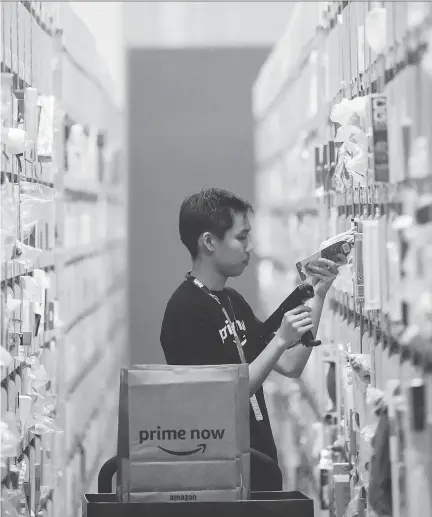  ?? JOSEPH NAIR/THE ASSOCIATED PRESS ?? An employee scans a product at the new Amazon Prime Now express delivery facility in Singapore on Thursday. Amazon’s e-commerce dominance in the U.S. is attributed in large part to the Amazon Prime service, which includes delivery discounts, music and...