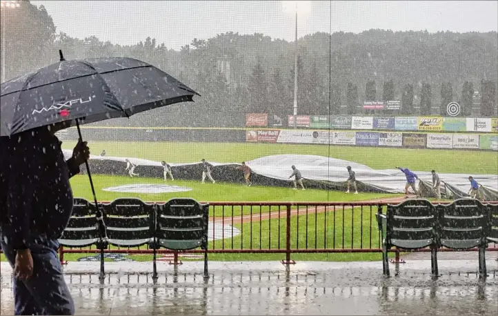  ?? Paul Buckowski / Times Union ?? Grounds crews cover the infield as heavy rain falls July 18 during the Tri-city Valleycats game against Equipe Quebec .