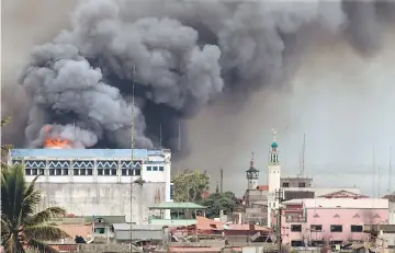  ?? — Reuters photo ?? Black smoke comes from a burning building in a commercial area of Osmena street in Marawi city, Philippine­s.