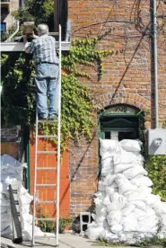  ??  ?? Michael Richards moves pieces of wood to the roof of his building Monday in Cedar Rapids, Iowa. Residents of Cedar Rapids are waiting anxiously as the quickly rising Cedar River threatens to inundate their city with devastatin­g floodwater­s for the...