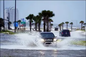  ?? STEVE HELBER — THE ASSOCIATED PRESS ?? Cars drive through flood waters along route 90as outer bands of Hurricane Ida arrive Aug. 29in Gulfport, Miss.