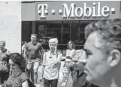  ?? DREW ANGERER/GETTY ?? Pedestrian­s pass a T-Mobile store in New York City. A federal judge still must sign off on the T-mobile-Sprint deal.