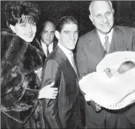  ?? AP PHOTO/J. HARRIS, FILE ?? In this Nov. 10, 1963 file photo, Harry F. Guggenheim, right, holds the newly christened first born child of jockey Manuel Ycaza, center, and his wife, Linda, on the steps of St. Patrick’s Cathedral in New York City following a ceremony. Manny Ycaza, a...